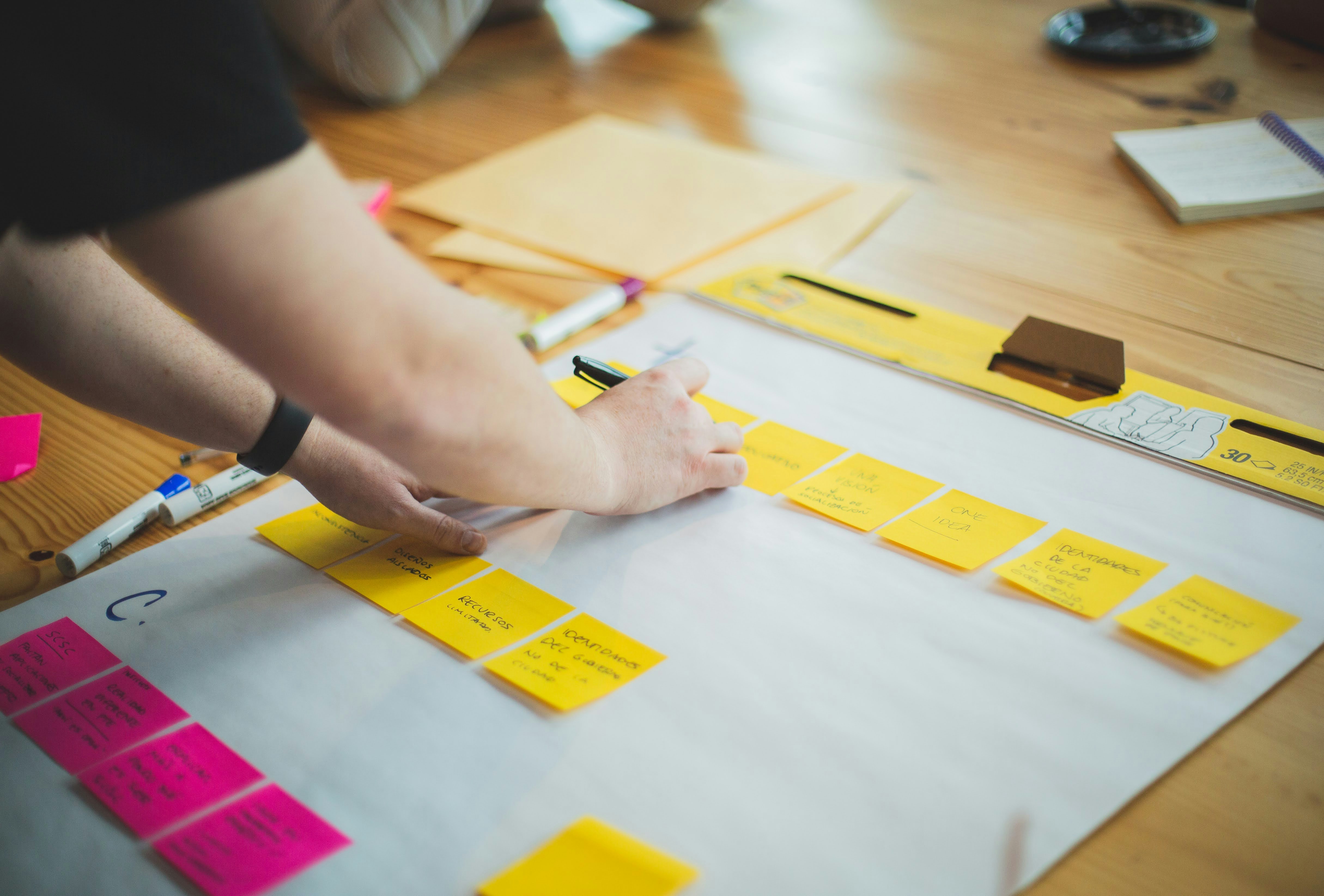 Someone leaning over a table and writing on sticky notes
